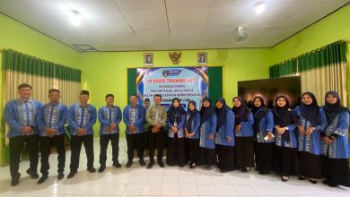 Foto bersama guru SMA Muhammadiyah 1 Simo mengenakan seragam batik biru dalam acara IHT Integrasi Coding dan Artificial Intelligence di aula sekolah. Di tengah barisan tampak narasumber berbaju krem dan Kepala Sekolah Ibu Dwitya Nadia Fatmawati berdiri di depan spanduk acara resmi.