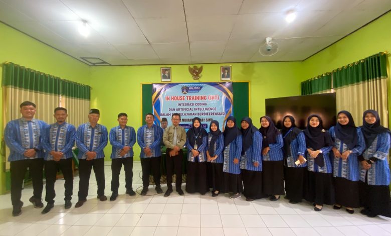 Foto bersama guru SMA Muhammadiyah 1 Simo mengenakan seragam batik biru dalam acara IHT Integrasi Coding dan Artificial Intelligence di aula sekolah. Di tengah barisan tampak narasumber berbaju krem dan Kepala Sekolah Ibu Dwitya Nadia Fatmawati berdiri di depan spanduk acara resmi.