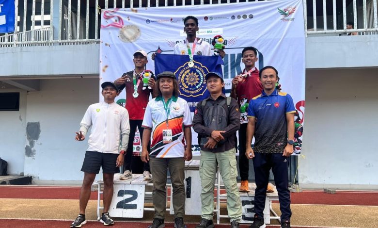 Mahasiswa Internasional UMP Ingo Godwil berdiri di podium juara satu memegang bendera Universitas Muhammadiyah Purwokerto pada ajang 1st Muhammadiyah Games 2026 di Stadion Mandala Krida Yogyakarta.