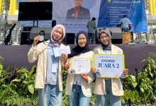 Tiga mahasiswi UMPWR berhijab dan mengenakan almamater krem, tersenyum bangga memegang medali dan sertifikat "Juara 2" di ajang EKKN 4 Universitas Tidar. Mereka berpose di depan panggung acara outdoor.