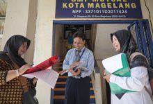 Tim monitoring Dinas Lingkungan Hidup Kota Magelang sedang memverifikasi berkas instrumen penilaian Sekolah Adiwiyata bersama guru SMP Mutual Magelang di depan gedung sekolah.