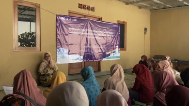Sekelompok wanita duduk di lantai mendengarkan ceramah di ruangan dengan spanduk PKM UMS ungu besar di latar belakang.