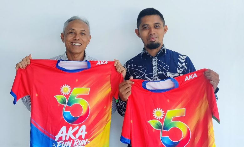 Rektor UMS Prof. Dr. Harun Joko Prayitno, M.Hum. (kiri) bersama perwakilan panitia menunjukkan jersey resmi AKA Fun Run 2026 berwarna merah kombinasi pelangi dengan logo angka 5.