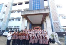 Foto bersama puluhan guru dan karyawan MI Muhammadiyah Danurejo Temanggung berbaju batik cokelat seragam dengan jajaran MI Muhammadiyah Ajibarang di depan gedung madrasah megah berlantai tiga dengan fasad biru abu-abu.