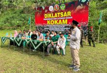 Suasana upacara pembukaan Diklatsar KOKAM Pekalongan 2026 di Lapangan Desa Rogoselo Doro dengan latar belakang spanduk besar bertuliskan Diklatsar KOKAM Marda Surya Cempaluk dan deretan tamu undangan di meja VIP.