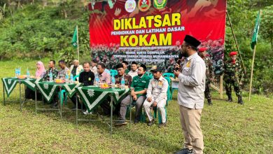 Suasana upacara pembukaan Diklatsar KOKAM Pekalongan 2026 di Lapangan Desa Rogoselo Doro dengan latar belakang spanduk besar bertuliskan Diklatsar KOKAM Marda Surya Cempaluk dan deretan tamu undangan di meja VIP.
