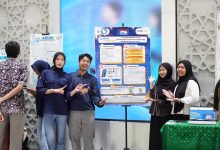Lima orang mahasiswa Teknik Informatika UMS berdiri tersenyum sambil berpose di depan poster infografis proyek inovasi teknologi mereka berjudul Lost and Found di Hall Gedung Induk Siti Walidah.