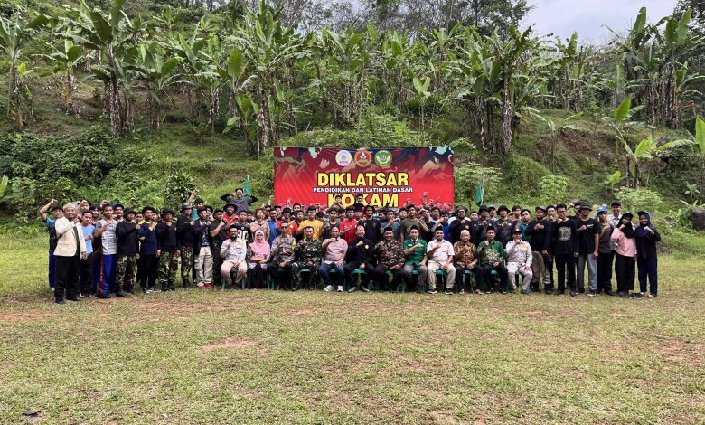 Jajaran instruktur, tamu undangan, dan puluhan peserta Diklatsar KOKAM Kabupaten Pekalongan berfoto bersama mengepalkan tangan di depan banner kegiatan di Lapangan Rogoselo Doro.
