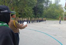 Instruktur dari Kafilah Penuntun Moh. Djazman UMS membacakan draf instruksi di depan barisan puluhan peserta upacara Diklat DSD Hizbul Wathan Kwarda Boyolali di lapangan terbuka.