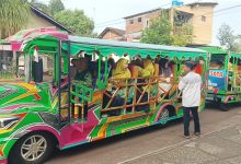 Jamaah wanita Muhammadiyah dan Aisyiyah Jepara berkerudung hijau dan kuning duduk di dalam kereta wisata hijau terintegrasi untuk berangkat pengajian.