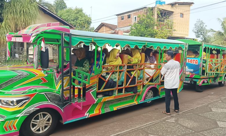 Jamaah wanita Muhammadiyah dan Aisyiyah Jepara berkerudung hijau dan kuning duduk di dalam kereta wisata hijau terintegrasi untuk berangkat pengajian.