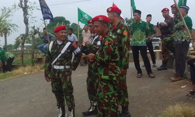 Personel Kokam Pakis Aji mengenakan seragam loreng sedang berjaga dan berkoordinasi dalam pengamanan Pengajian PDM Jepara di Sowan Kidul.