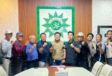 Sekelompok pria berpose di depan pemandangan laut yang indah dengan tinju mengepal, melambangkan persaudaraan dan semangat juang "BikersMU Korwil Lampung".