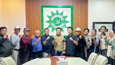 Sekelompok pria berpose di depan pemandangan laut yang indah dengan tinju mengepal, melambangkan persaudaraan dan semangat juang "BikersMU Korwil Lampung".