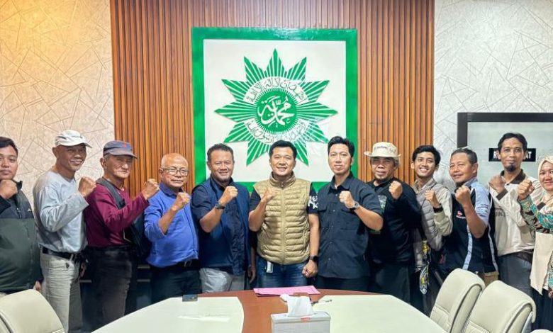 Sekelompok pria berpose di depan pemandangan laut yang indah dengan tinju mengepal, melambangkan persaudaraan dan semangat juang "BikersMU Korwil Lampung".