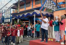 Sekretaris Dinas Pendidikan Kota Surakarta Tarno mengangkat bendera start hitam-putih di panggung didampingi panitia saat melepas peserta Jalan Sehat Keluarga dalam acara Family Day SD Muhammadiyah 1 Solo.