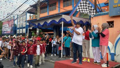 Sekretaris Dinas Pendidikan Kota Surakarta Tarno mengangkat bendera start hitam-putih di panggung didampingi panitia saat melepas peserta Jalan Sehat Keluarga dalam acara Family Day SD Muhammadiyah 1 Solo.