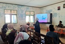 Dr. Laili Etika Rahmawati sedang memaparkan materi parenting menggunakan mikrofon di depan wali murid di dalam ruang kelas madrasah.