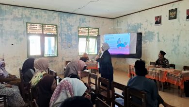 Dr. Laili Etika Rahmawati sedang memaparkan materi parenting menggunakan mikrofon di depan wali murid di dalam ruang kelas madrasah.