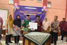 Perwakilan Pemkab Grobogan bersama perwakilan mahasiswa UNIMUS memegang dokumen kerja sama di depan banner Grand Launching PPK Ormawa IMM Ahmad Dahlan.