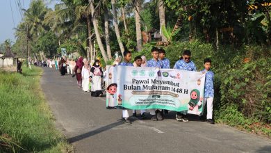 Siswa Perguruan Muhammadiyah Bayan membentangkan spanduk Pawai Menyambut Bulan Muharram 1448 H di jalan pedesaan Purworejo.