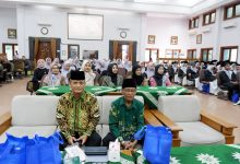 Suasana rapat koordinasi pengurus Muhammadiyah secara lesehan menggunakan laptop di dalam gedung serbaguna.
