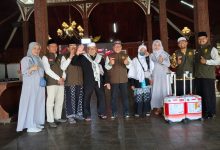 Foto bersama jajaran pengurus organisasi bersama jemaah haji kader Muhammadiyah di dalam gedung pendopo berarsitektur tradisional.