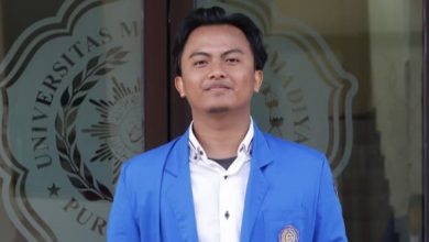 Wafi Fadhlurrahman, mahasiswa bahasa arab juara desain grafis nasional dari UMP berdiri mengenakan jas almamater biru.