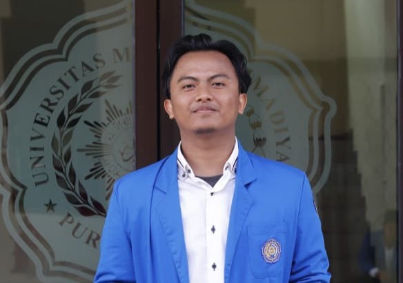 Wafi Fadhlurrahman, mahasiswa bahasa arab juara desain grafis nasional dari UMP berdiri mengenakan jas almamater biru.