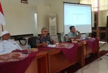 Suasana sidang pleno reorganisasi pengurus HW Drumband Cilacap periode 2025-2028 di gedung BLK-I Cilacap, menampilkan tiga orang pengurus di meja pimpinan dan layar proyektor susunan pengurus.