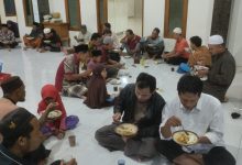 Jemaah Masjid Al Muttaqin Kedung Jepara sedang makan bersama duduk bersila di lantai dalam acara Jumat Berkah.