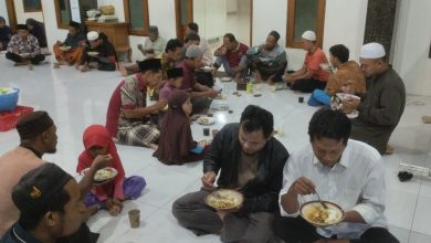 Jemaah Masjid Al Muttaqin Kedung Jepara sedang makan bersama duduk bersila di lantai dalam acara Jumat Berkah.