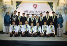 Para siswa wisudawan tahfidz MI Muhammadiyah Malebo Temanggung foto bersama di atas panggung mengenakan samir wisuda dan jas hitam.