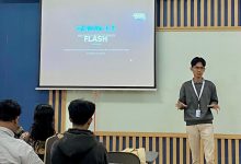Muhammad Hasbi Assidiqi mahasiswa UMS lolos Google Student Ambassador 2026 sedang berdiri memberikan presentasi materi Gemini 3.5 Flash di depan layar proyektor ruang kelas.