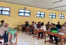 Foto sekelompok pria yang sedang serius mengikuti pelatihan aplikasi SatuMu MASA di dalam sebuah ruang kelas dengan bangku kayu dan dinding kuning. Tampak narasumber di depan kelas sedang mengarahkan peserta yang sedang mengoperasikan laptop.
