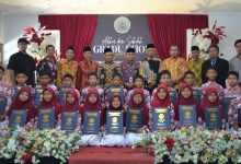 Siswa kelas VI MI Muhammadiyah Purwodadi memegang map kelulusan bersama para guru dan pengurus Majelis Dikdasmen PDM Temanggung di atas panggung graduation ceremony.