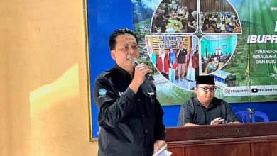 Drs. Suyatmin Waskito Adi, M.Si, dari DKPTI UMS, sedang memberikan sambutan pada peluncuran Musuk IbuPreneur Village. Ia memegang mikrofon dan berdiri di depan spanduk acara.