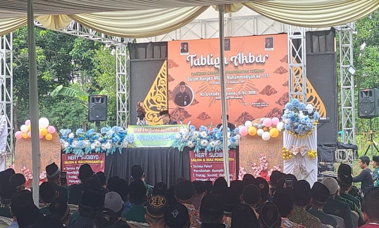Sebuah pemandangan luas dari dalam tenda besar, memperlihatkan ratusan jemaah yang duduk khusyuk menghadap panggung utama yang dihiasi dekorasi wayang gunungan dan spanduk Tabligh Akbar Milad ke-117 PCM Tersono Batang. Panggung menampilkan pembicara di tengah kerumunan yang tertib.