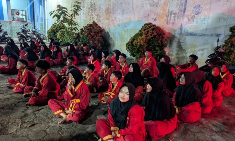 Puluhan kader muda Tapak Suci Blora mengenakan seragam merah khas pesilat Muhammadiyah duduk bersila di halaman saat mengikuti materi ruangan malam hari pada Ujian Kenaikan Tingkat (UKT) di Kunduran.