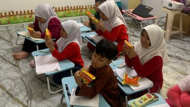 Anak-anak di Sanggar Bimbingan Malaysia sedang serius membaca label kemasan makanan saat mengikuti kegiatan edukasi gizi seimbang.