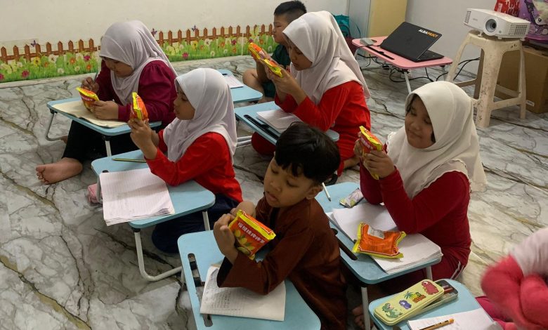 Anak-anak di Sanggar Bimbingan Malaysia sedang serius membaca label kemasan makanan saat mengikuti kegiatan edukasi gizi seimbang.