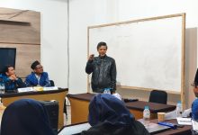 Narasumber sedang memaparkan materi tata kelola organisasi di depan papan tulis saat rapat kerja pimpinan sekolah Muhammadiyah.