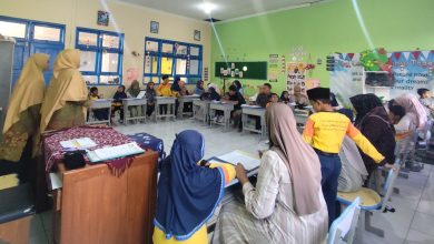 Foto suasana dalam ruang kelas di MIM Kauman saat momen pembagian rapor unik. Siswa, orang tua, dan guru terlihat duduk bersama di meja siswa, berinteraksi dan berpartisipasi dalam aktivitas parenting imersif.