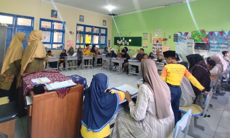 Foto suasana dalam ruang kelas di MIM Kauman saat momen pembagian rapor unik. Siswa, orang tua, dan guru terlihat duduk bersama di meja siswa, berinteraksi dan berpartisipasi dalam aktivitas parenting imersif.