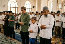 Seorang anak kecil sedang khusyuk shalat berjamaah di saf depan masjid bersama jamaah dewasa, menggambarkan hukum anak kecil di saf depan.