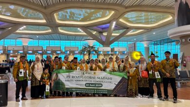 Sekelompok jamaah umroh dari KBIHU Ar-Roudloh Temanggung yang mengenakan batik identitas sedang berfoto bersama di terminal keberangkatan Bandara Yogyakarta International Airport (YIA), memegang spanduk pelepasan tanggal 22 Juni 2026.