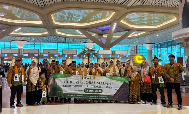 Sekelompok jamaah umroh dari KBIHU Ar-Roudloh Temanggung yang mengenakan batik identitas sedang berfoto bersama di terminal keberangkatan Bandara Yogyakarta International Airport (YIA), memegang spanduk pelepasan tanggal 22 Juni 2026.