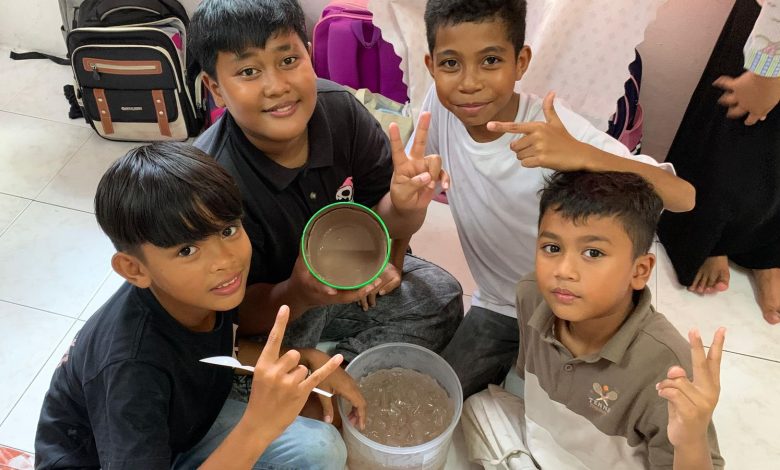Empat anak laki-laki di Malaysia menunjukkan es krim cokelat hasil eksperimen sains sederhana dalam program KKN Mahasiswa UMS,