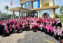 Foto grup besar sekitar seratus wanita anggota 'Aisyiyah mengenakan seragam hitam dan hijab merah muda, tersenyum dan melambaikan tangan di depan Gedung Dakwah 'Aisyiyah Kabupaten Temanggung pada hari yang cerah.