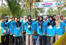 Sekelompok siswi berhijab berpose di depan gerbang tenda "KABUPATEN CILACAP" saat Jambore di pantai.